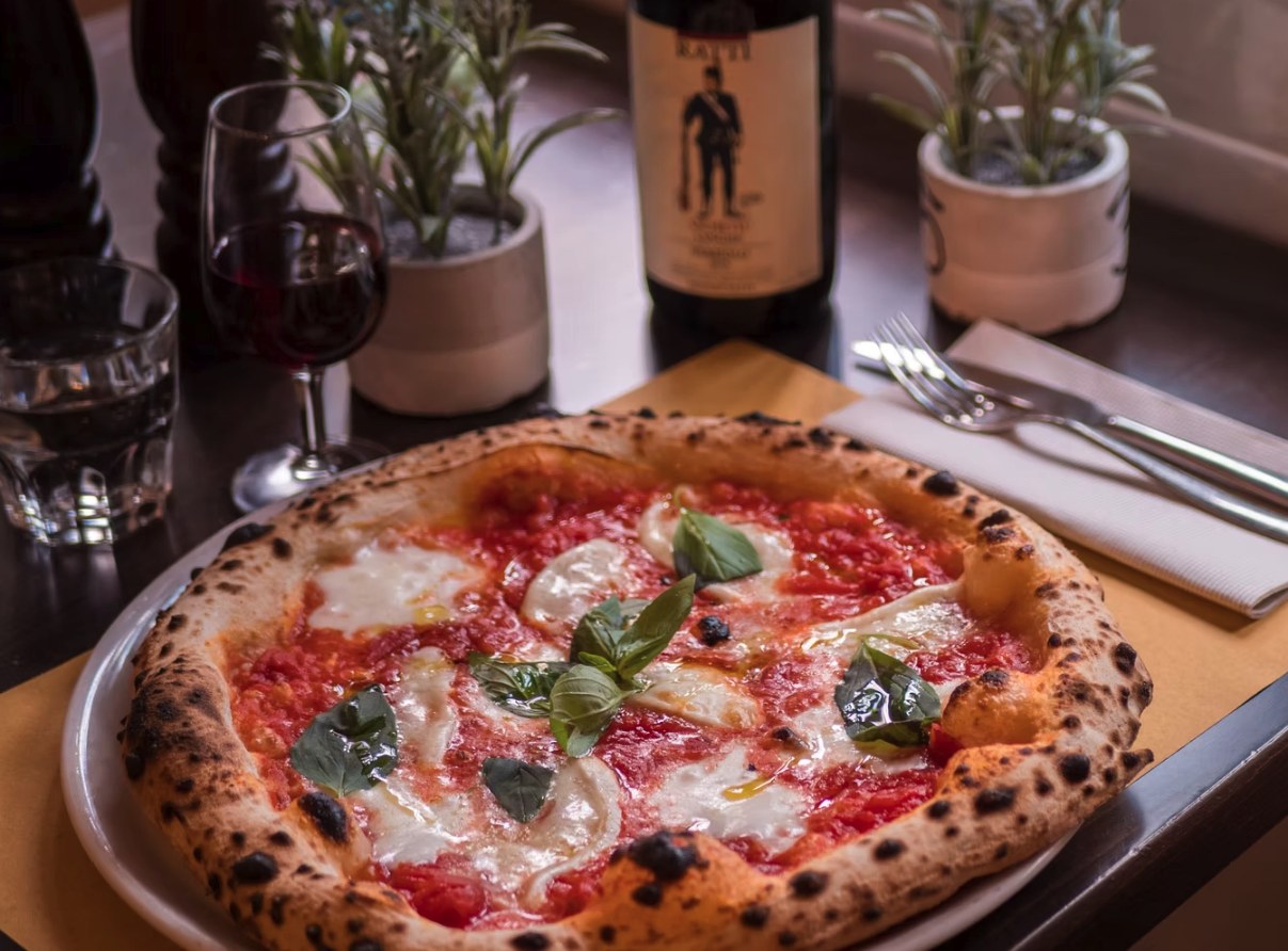 Pizza margherita appena sfornata, con un calice di vino